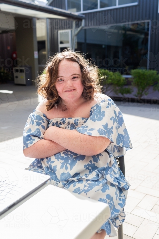 Portrait of female teenager with down syndrome working at cafe table with laptop - Australian Stock Image