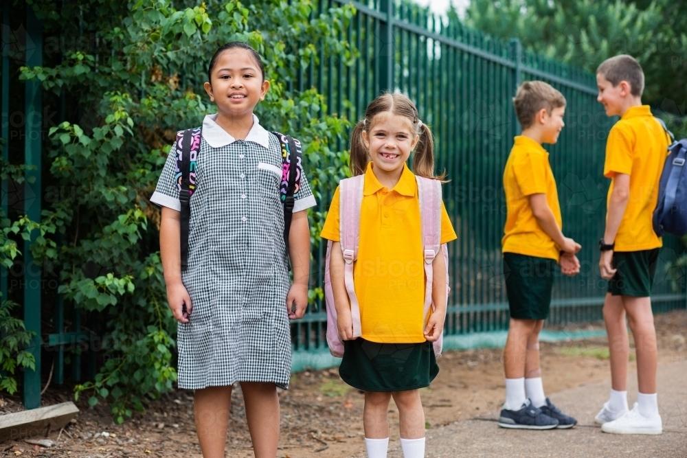 Portrait of happy Australian school kids beside school fence going to school - Australian Stock Image