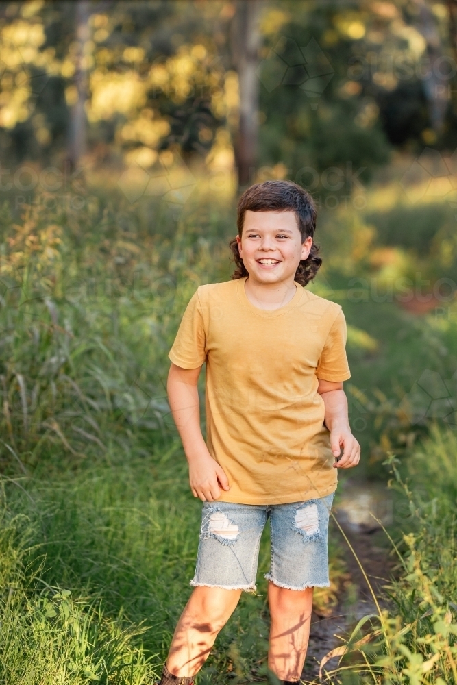 Portrait of happy boy wearing yellow shirt in Australian country bush setting - Australian Stock Image