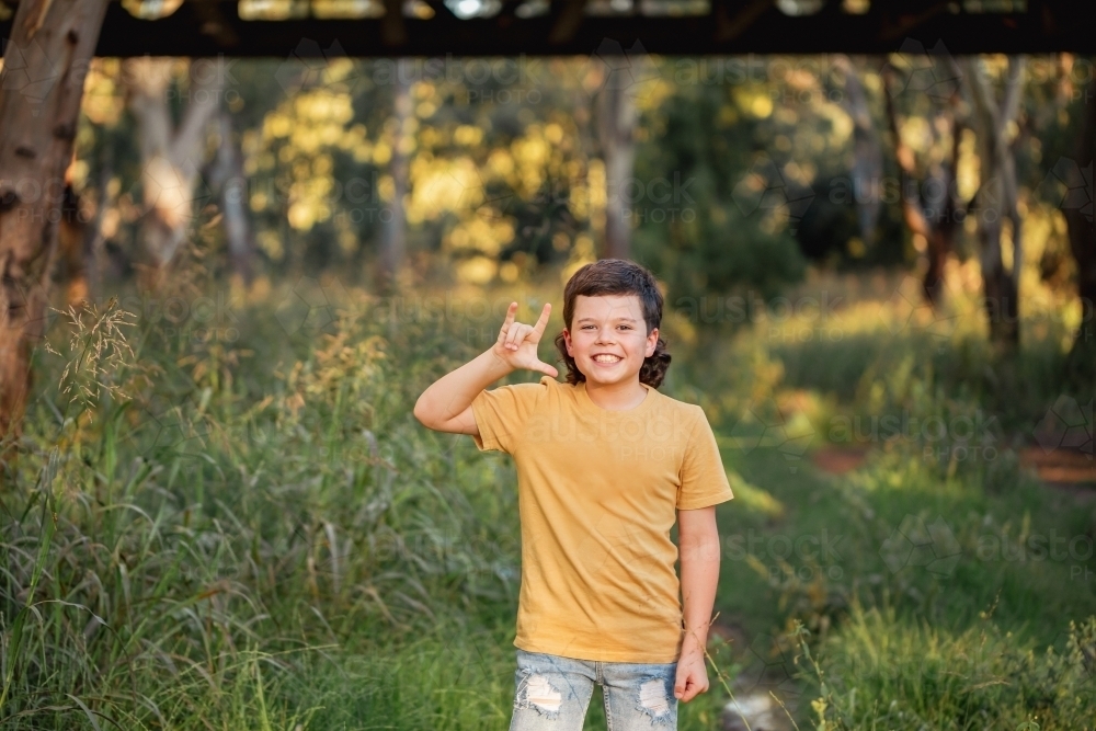 Portrait of happy boy wearing yellow shirt in Australian country bush setting - Australian Stock Image