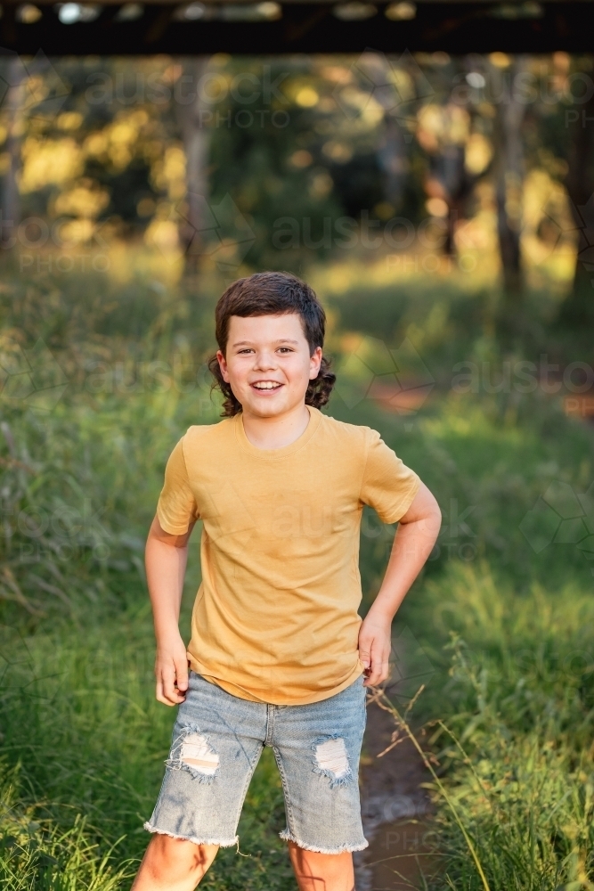 Portrait of happy boy wearing yellow shirt in Australian country bush setting - Australian Stock Image