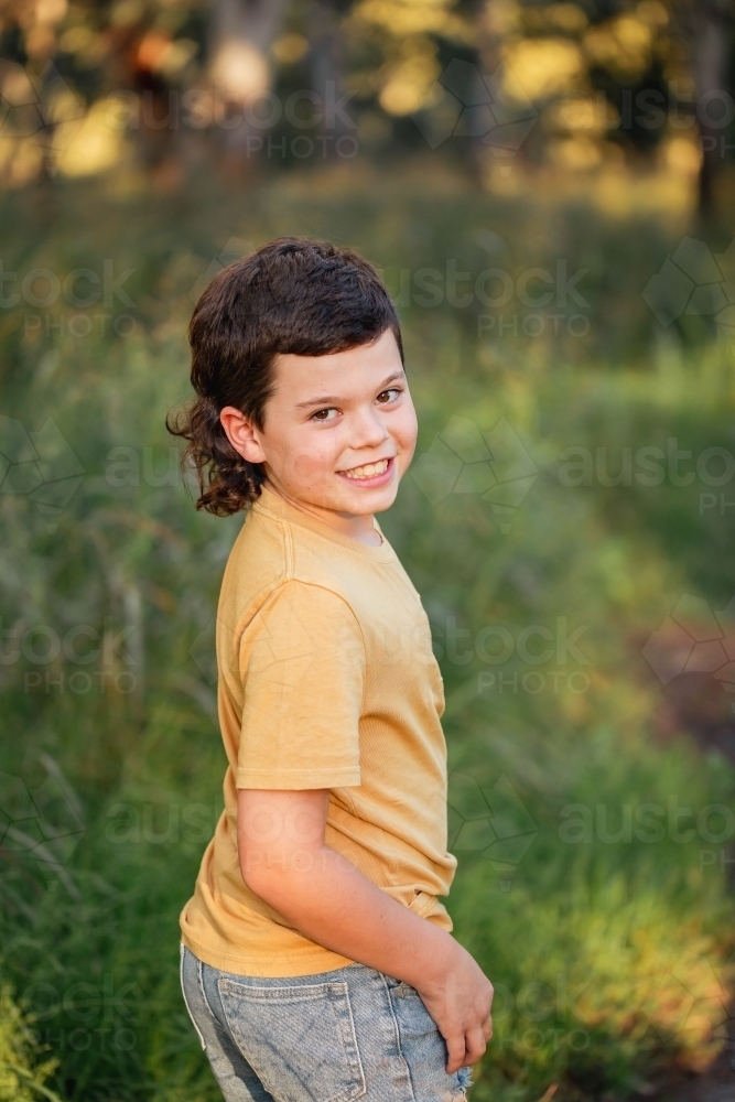 Portrait of happy boy wearing yellow shirt in Australian country bush setting - Australian Stock Image