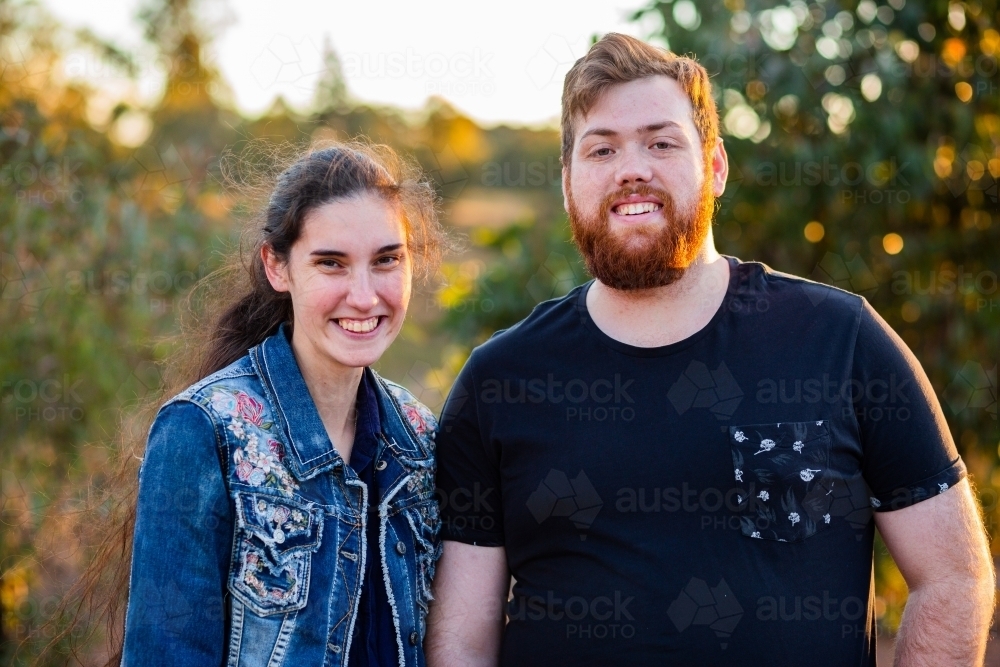 Portrait of happy couple side by side outside in casual clothing - Australian Stock Image