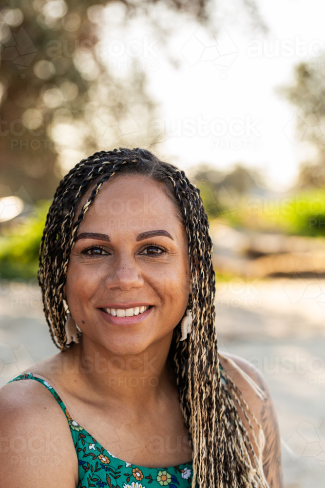 Portrait of happy First Nations Australian woman at the beach with box braids - Australian Stock Image
