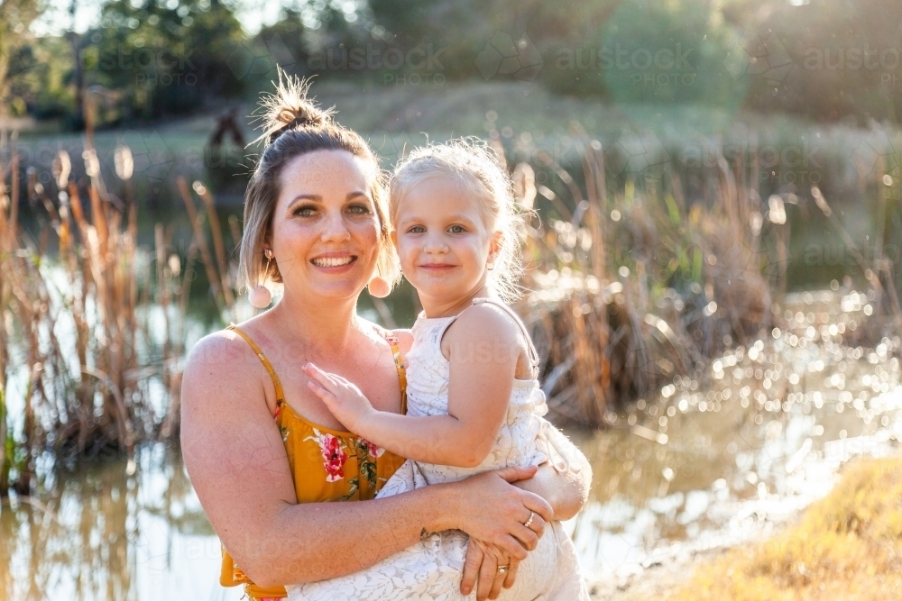 Portrait of happy mother in her thirties with daughter outside - Australian Stock Image
