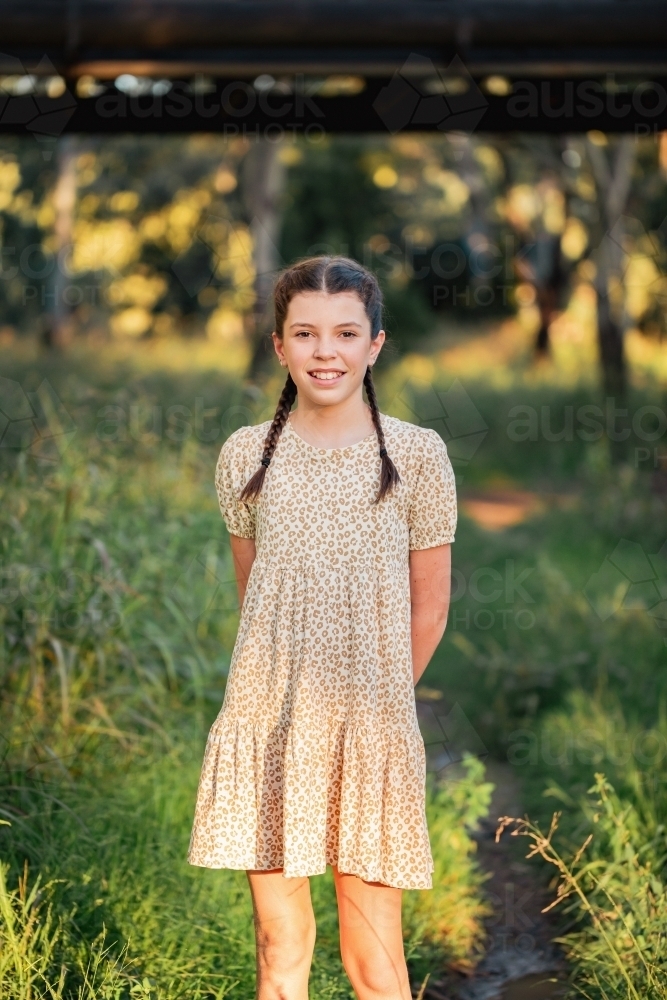 Portrait of happy pre-teen girl wearing dress in Australian country bush setting - Australian Stock Image