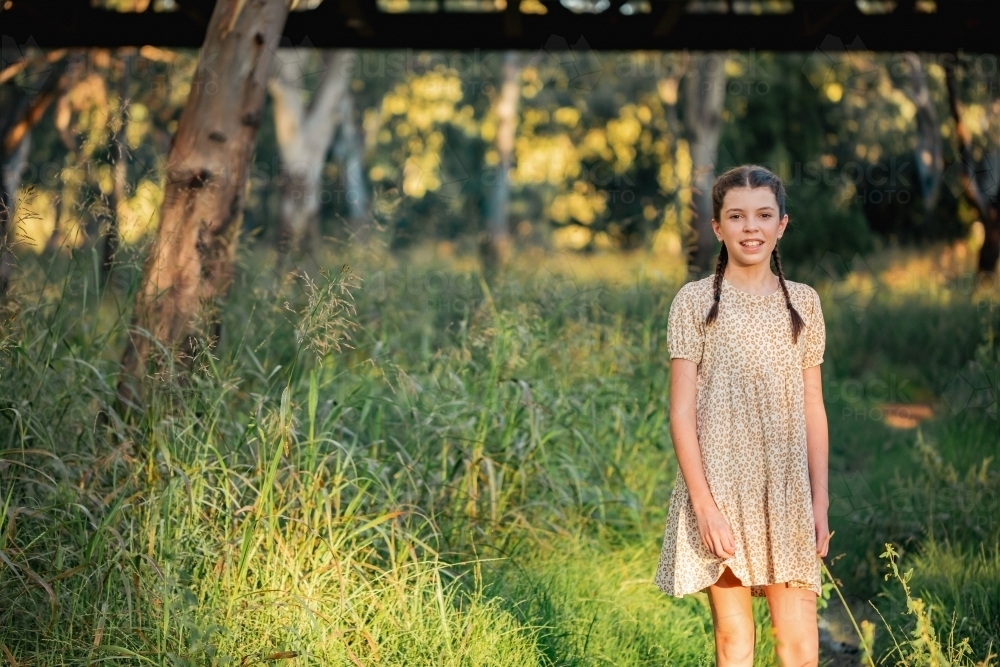 Portrait of happy pre-teen girl wearing dress in Australian country bush setting - Australian Stock Image