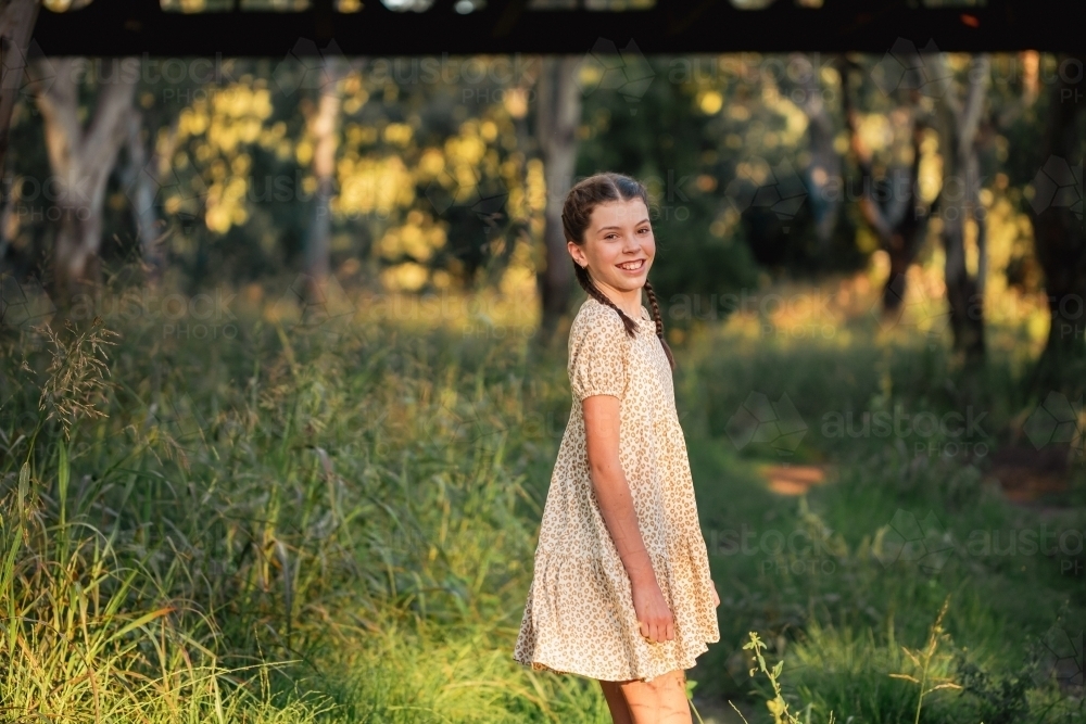 Portrait of happy pre-teen girl wearing dress in Australian country bush setting - Australian Stock Image