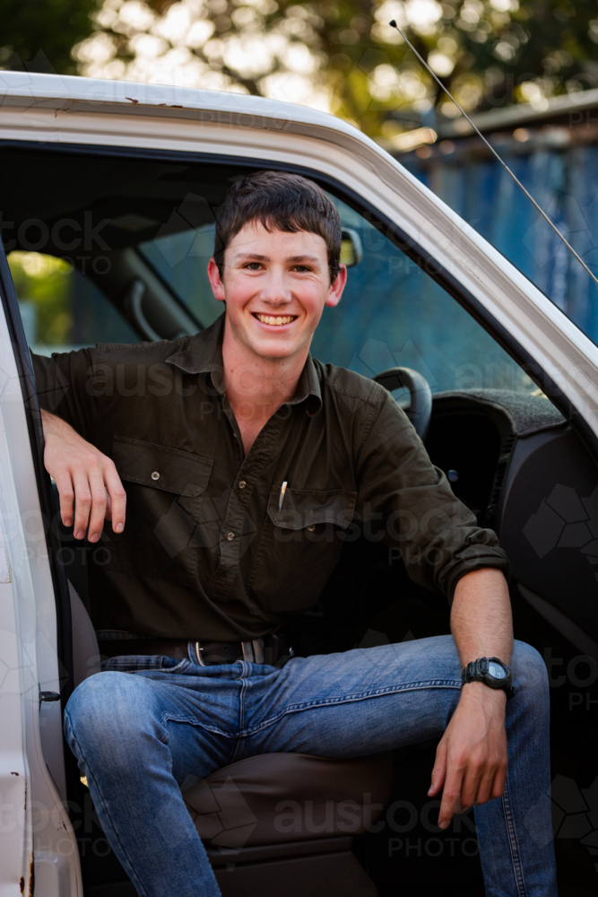 Portrait of happy smiling teenaged young person sitting in his first car a ute in country setting - Australian Stock Image