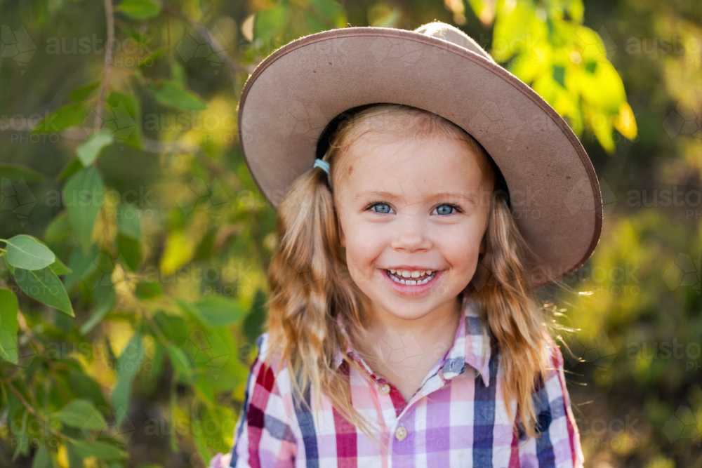 Portrait of happy smiling young Australian child outdoors in green bushland with gum leaves - Australian Stock Image