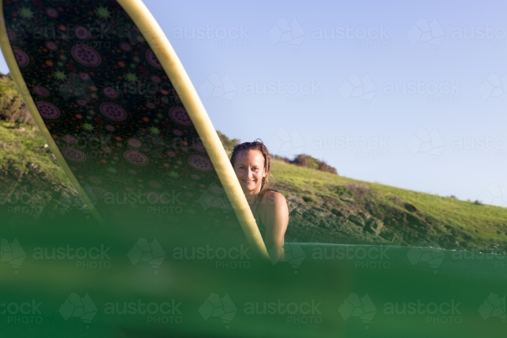 Portrait of happy, smiling young surfer in water with surfboard - Australian Stock Image