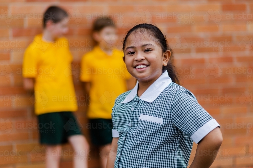 Portrait of happy young Aussie school girl of Filipino ethnicity smiling and wearing a dress - Australian Stock Image