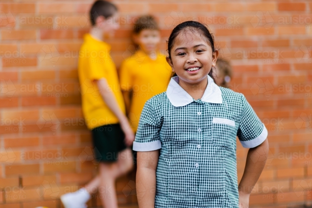 Portrait of happy young Aussie school girl of Filipino ethnicity smiling and wearing a dress - Australian Stock Image