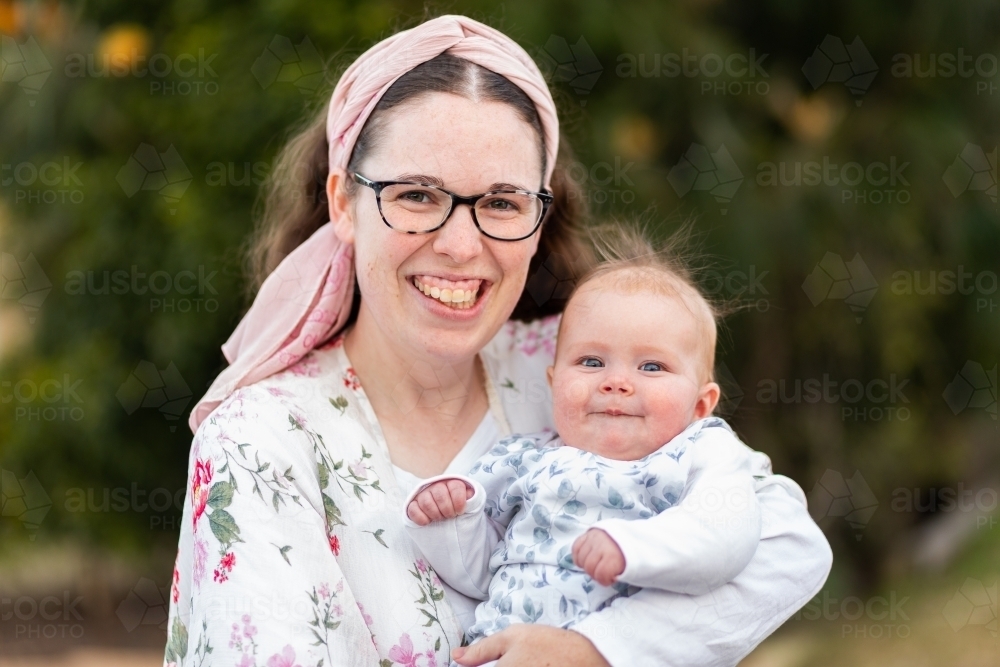 Portrait of happy young mum in her twenties with five month old baby - Australian Stock Image