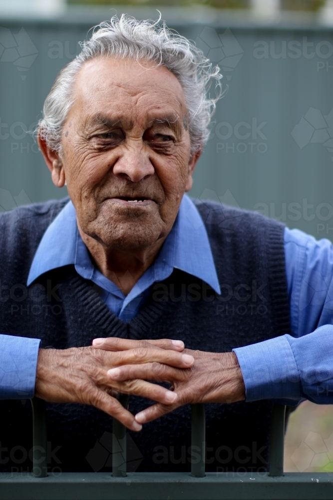 Portrait of male Aboriginal elder leaning on a fence - Australian Stock Image