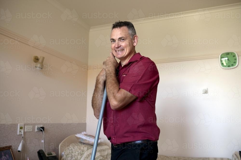 Portrait of Male Nursing Home Staff Member Doing Cleaning Rounds - Australian Stock Image