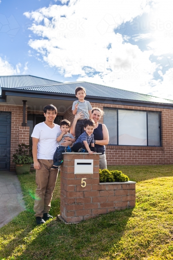 portrait of mixed race Chinese Australian family outside home with kids sitting on mailbox - Australian Stock Image