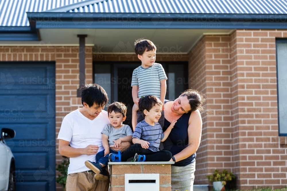 portrait of mixed race Chinese Australian family outside home with kids sitting on mailbox - Australian Stock Image