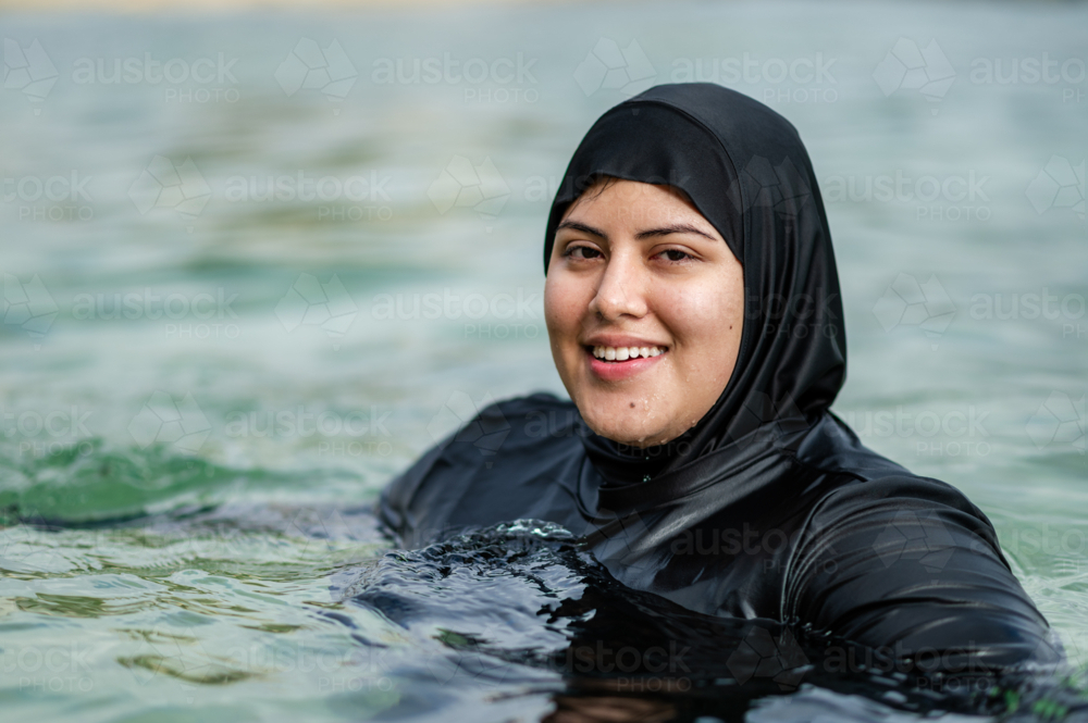 Portrait of mixed-race woman in burkini inside ocean pool on sunny day - Australian Stock Image