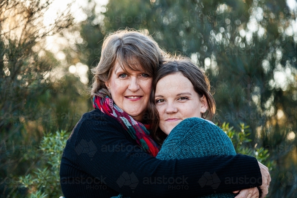 Portrait of mother and daughter embracing in hug - Australian Stock Image