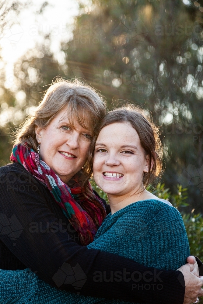 Portrait of mother and daughter embracing in hug - Australian Stock Image