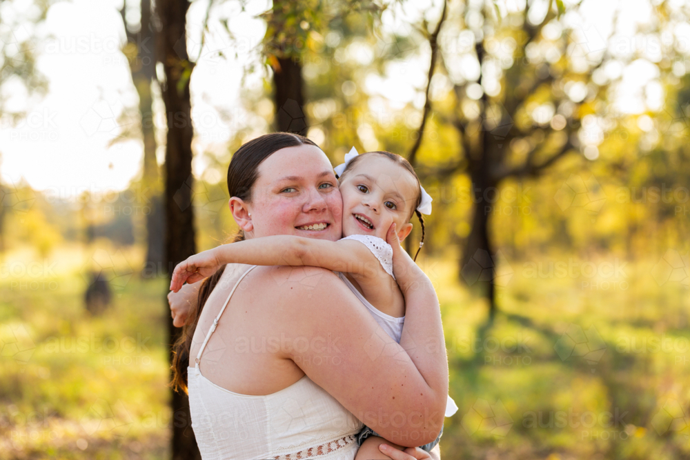 portrait of mother and daughter hugging each other in green country setting - Australian Stock Image
