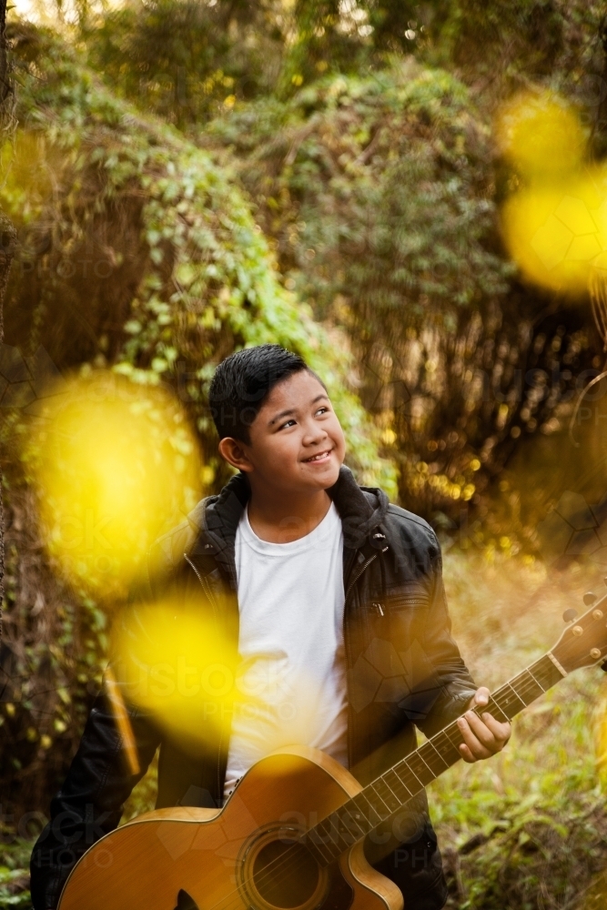 Portrait of musician through trees bokeh foreground - Australian Stock Image