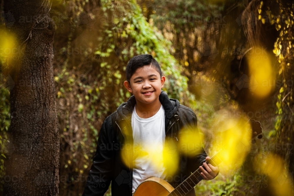 Portrait of musician through trees bokeh foreground - Australian Stock Image