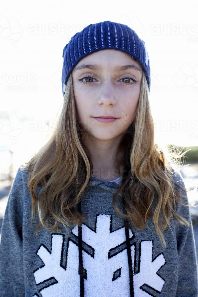 Portrait of pre teen girl wearing a beanie and a hoodie. - Australian Stock Image