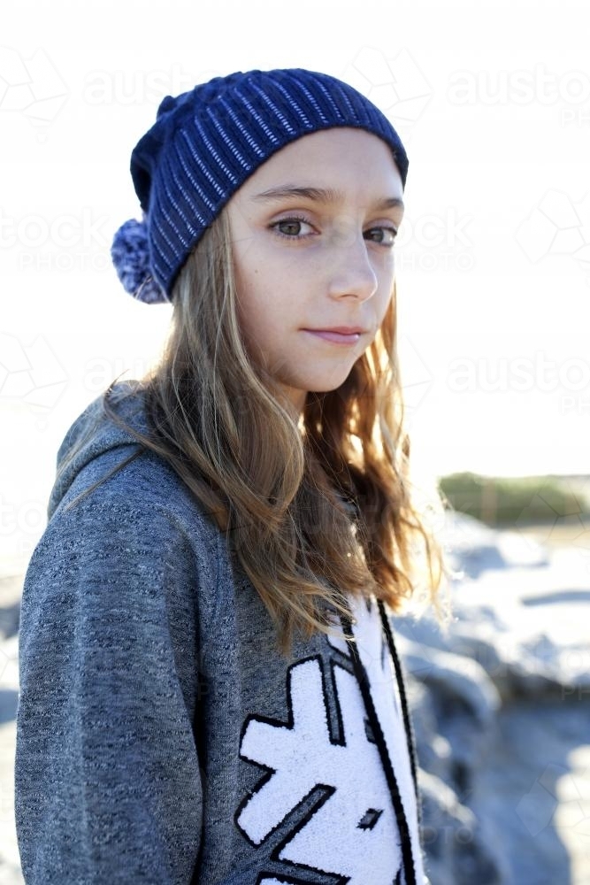 Portrait of pre teen girl with beanie on standing sideways - Australian Stock Image