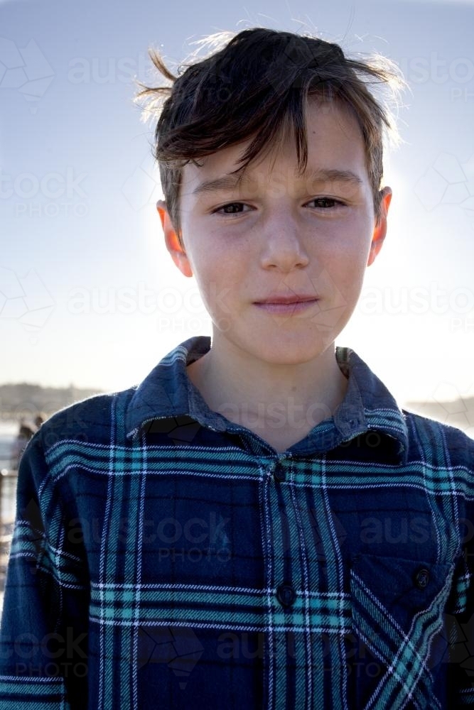 Portrait of serious boy with afternoon light behind - Australian Stock Image