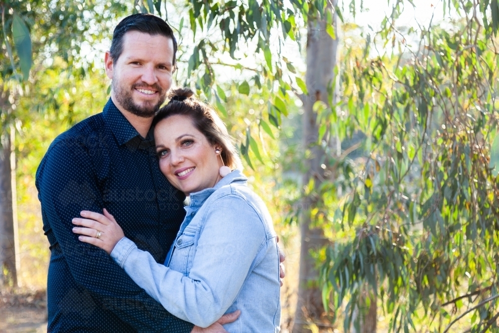Portrait of smiling couple with copy space and gum leaves - Australian Stock Image