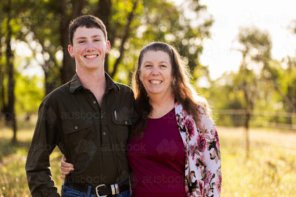 portrait of smiling middle aged woman and teenaged son together in paddock - Australian Stock Image