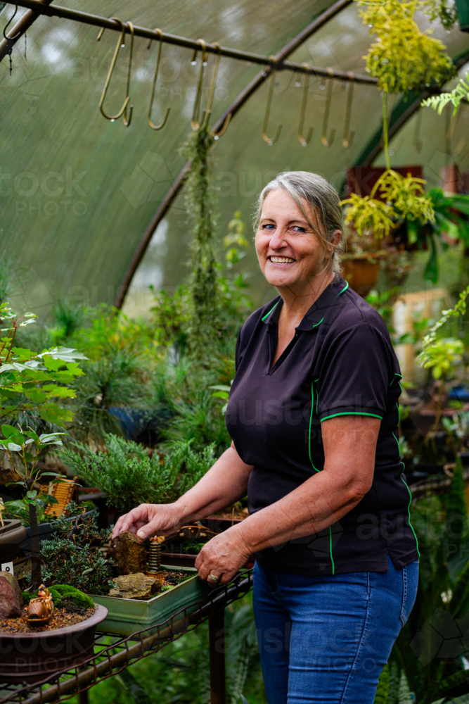 Image of Portrait of smiling middle aged woman working in greenhouse at ...