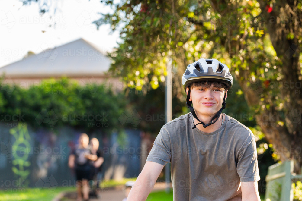 portrait of smiling teen boy wearing bike helmet in alleyway in country town - Australian Stock Image