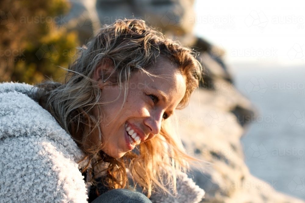 Portrait of smiling young woman on coastal clifftop at sunrise - Australian Stock Image