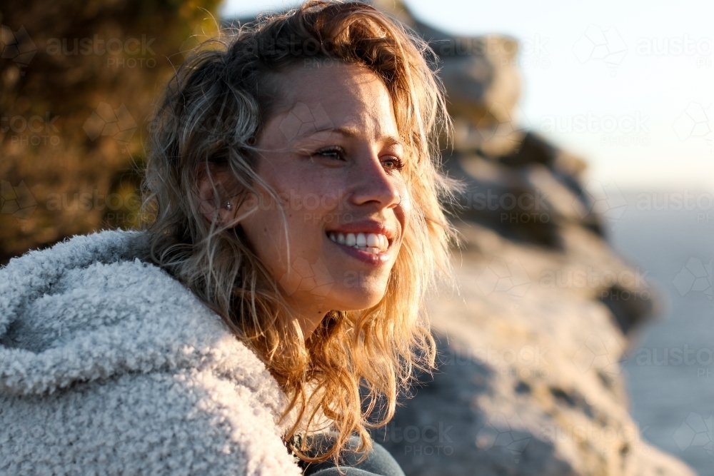 Portrait of smiling young woman on coastal clifftop at sunrise - Australian Stock Image