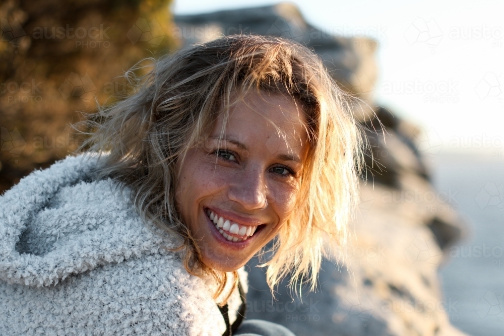 Portrait of smiling young woman on coastal clifftop at sunrise - Australian Stock Image
