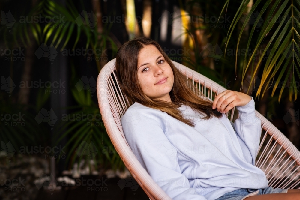 portrait of teen girl, sitting on chair outdoors - Australian Stock Image