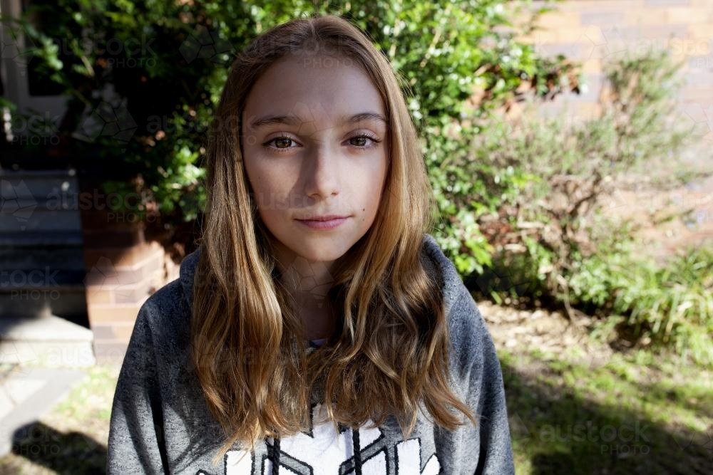 Portrait of teen girl wearing grey hoodie in the front yard - Australian Stock Image