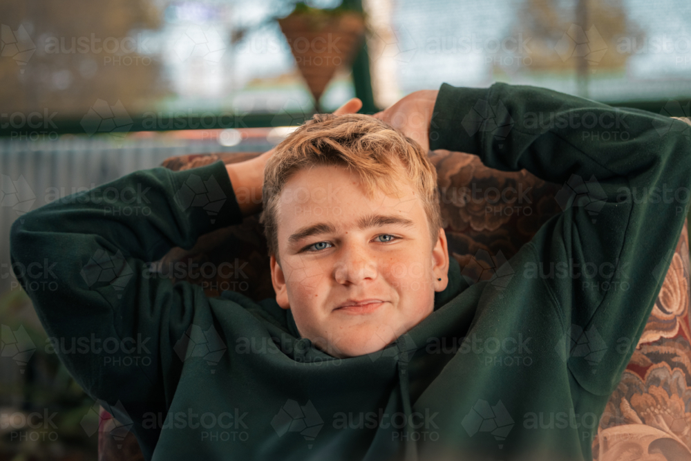 Portrait of teenage boy relaxing on outdoor chair - Australian Stock Image