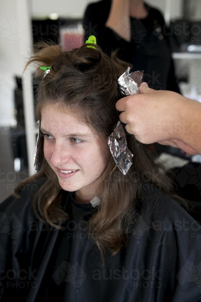 Portrait of teenage girl getting foils at a hairdresser - Australian Stock Image