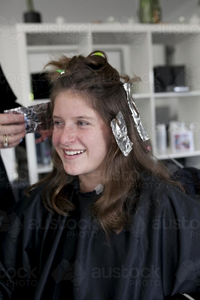 Portrait of teenage girl getting foils at a hairdresser - Australian Stock Image