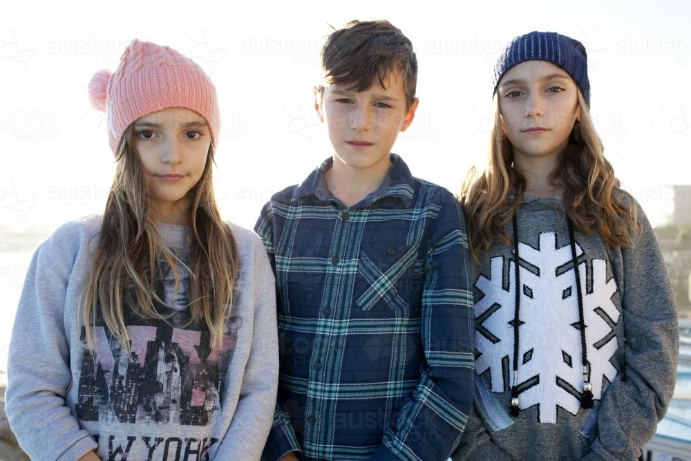 Portrait of three kids standing in the afternoon light - Australian Stock Image