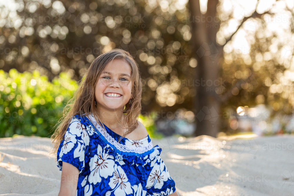 Portrait of Torres Strait Islander child smiling outside in traditional floral dress - Australian Stock Image