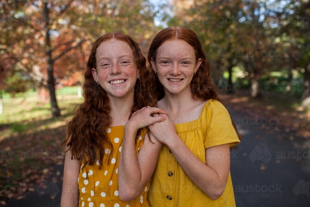Portrait of two girls in a street lined with Autumn trees - Australian Stock Image