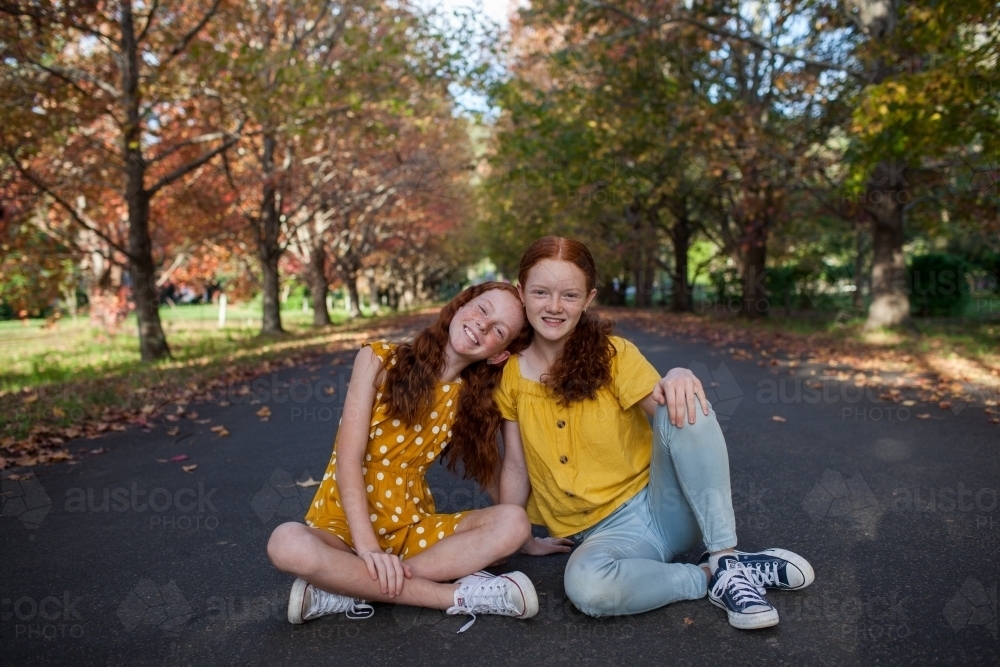 Portrait of two girls in a street lined with Autumn trees - Australian Stock Image