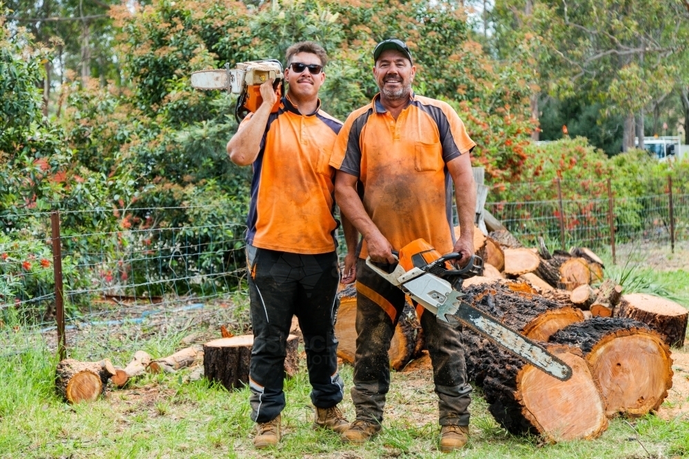 Portrait of two happy aussie blokes with chainsaws - lumberjack tree felling services - Australian Stock Image