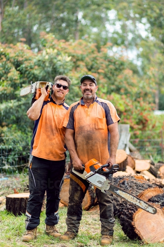 Portrait of two happy aussie blokes with chainsaws - lumberjack tree felling services - Australian Stock Image