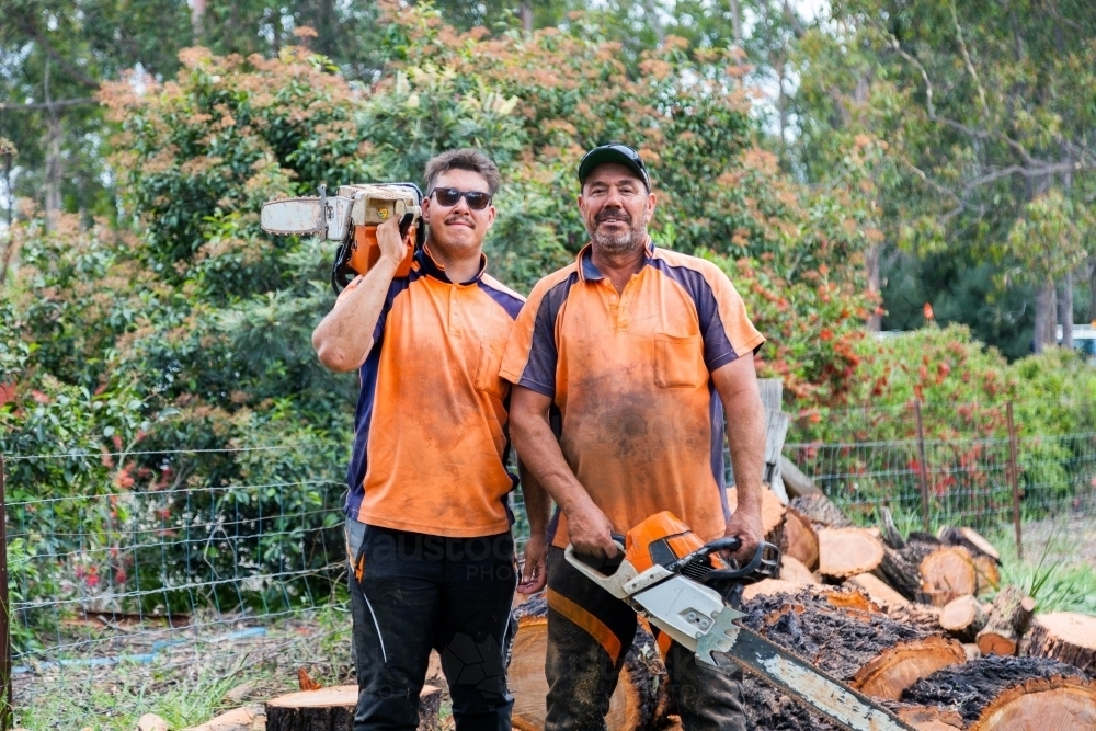 Portrait of two happy aussie blokes with chainsaws - lumberjack tree felling services - Australian Stock Image